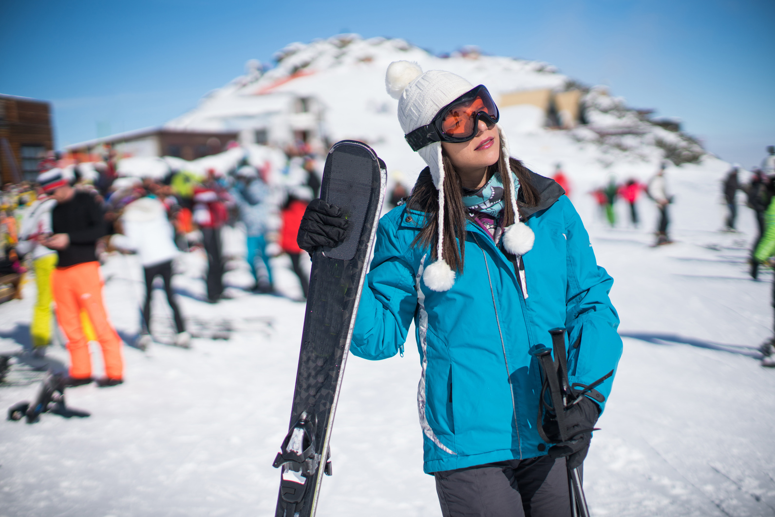 a woman in a blue jacket holding a pair of skis