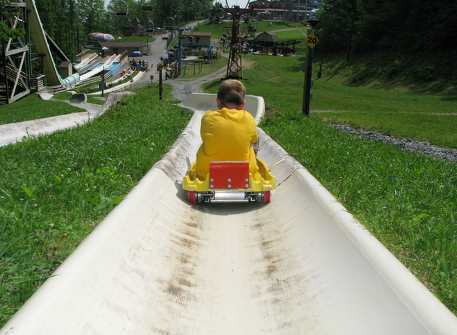 a young boy riding on a roller coaster at an amusement park